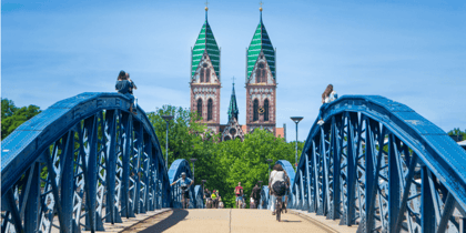 Blick über die blaue Schwabentorbrücke auf das Freiburger Münster im Stadtzentrum von Freiburg.