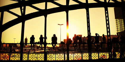 Menschen auf einer historischen Stahlbrücke in Hamburg bei Sonnenuntergang.