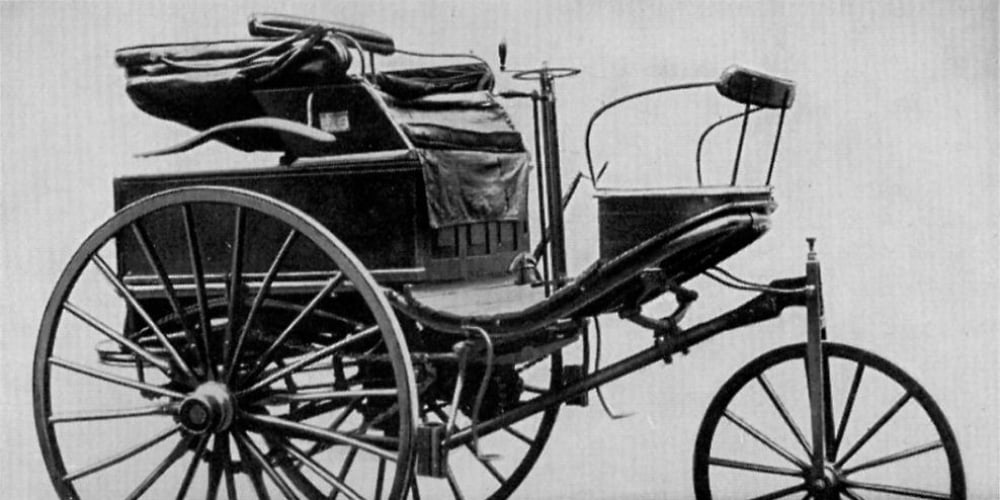Historischer dreirädriger Motorwagen in einer Schwarz-Weiß-Aufnahme.