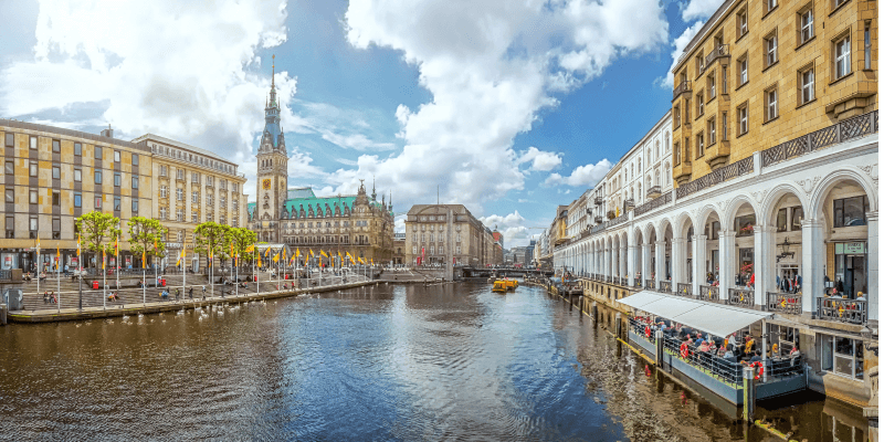 Hamburger Rathaus und Alsterarkaden am Alsterfleet im Stadtzentrum von Hamburg bei sonnigem Himmel.