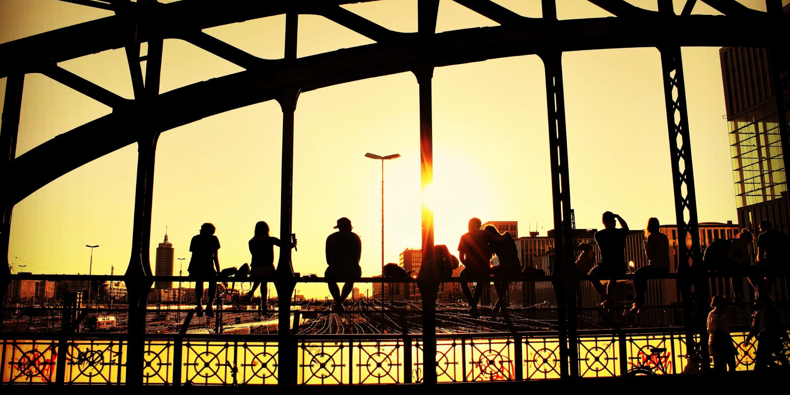 Menschen auf einer historischen Stahlbrücke in Hamburg bei Sonnenuntergang.