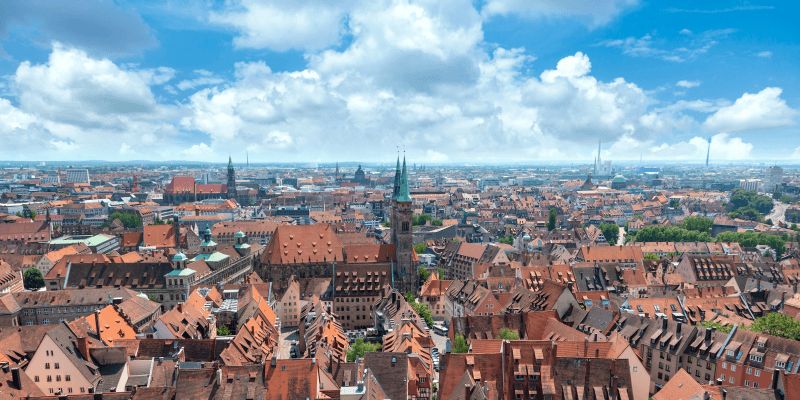 Panoramablick über die historische Altstadt von Nürnberg mit ihren roten Dächern, Kirchen und Wahrzeichen unter einem wolkenreichen Himmel.
