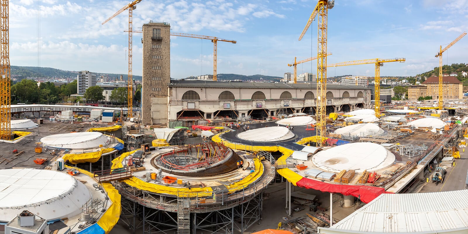 Großbaustelle des Bahnprojekts Stuttgart 21 mit Kränen und Bahnhof im Hintergrund.